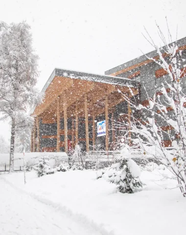 Scène d'hiver avec le bâtiment du palais à Megève et des arbres, tous recouverts d'une épaisse couche de neige.