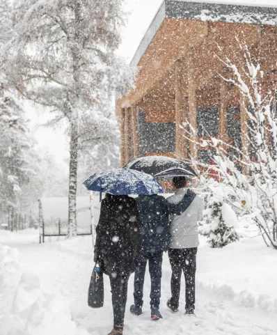 Trois personnes marchant joyeusement dans la neige, entourées d'un paysage hivernal paisible.