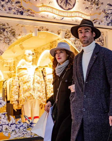 Un homme et une femme marchent ensemble devant une boutique, illustrant une sortie agréable.