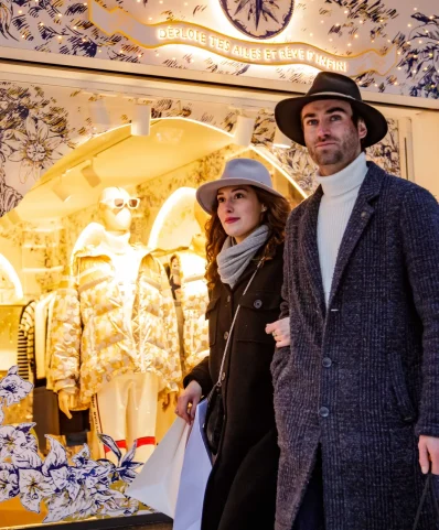 Un homme et une femme marchent ensemble devant une boutique, illustrant une sortie agréable.